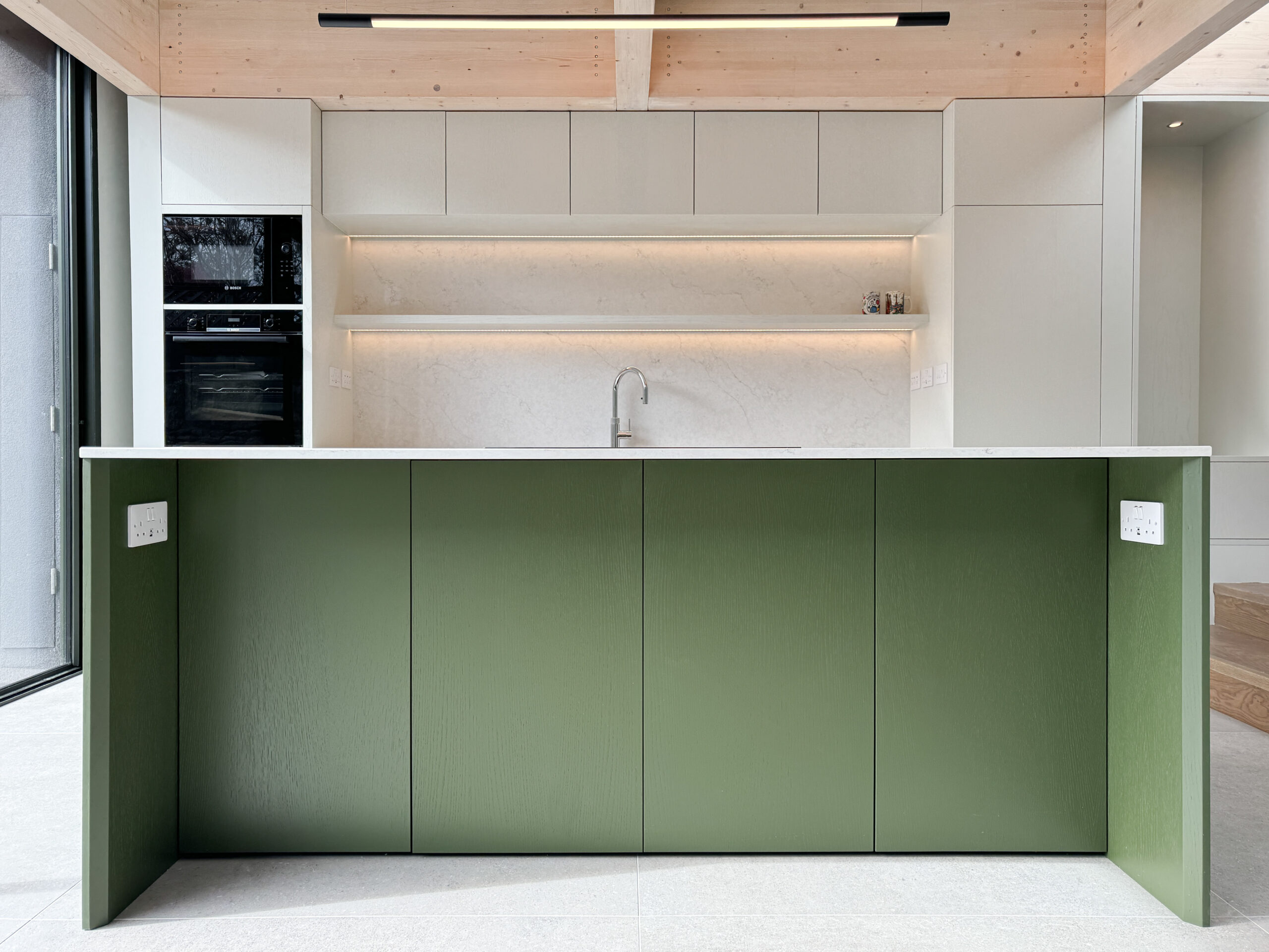 Custom made modern kitchen and utility space with large island, quartz worktop, hidden doors