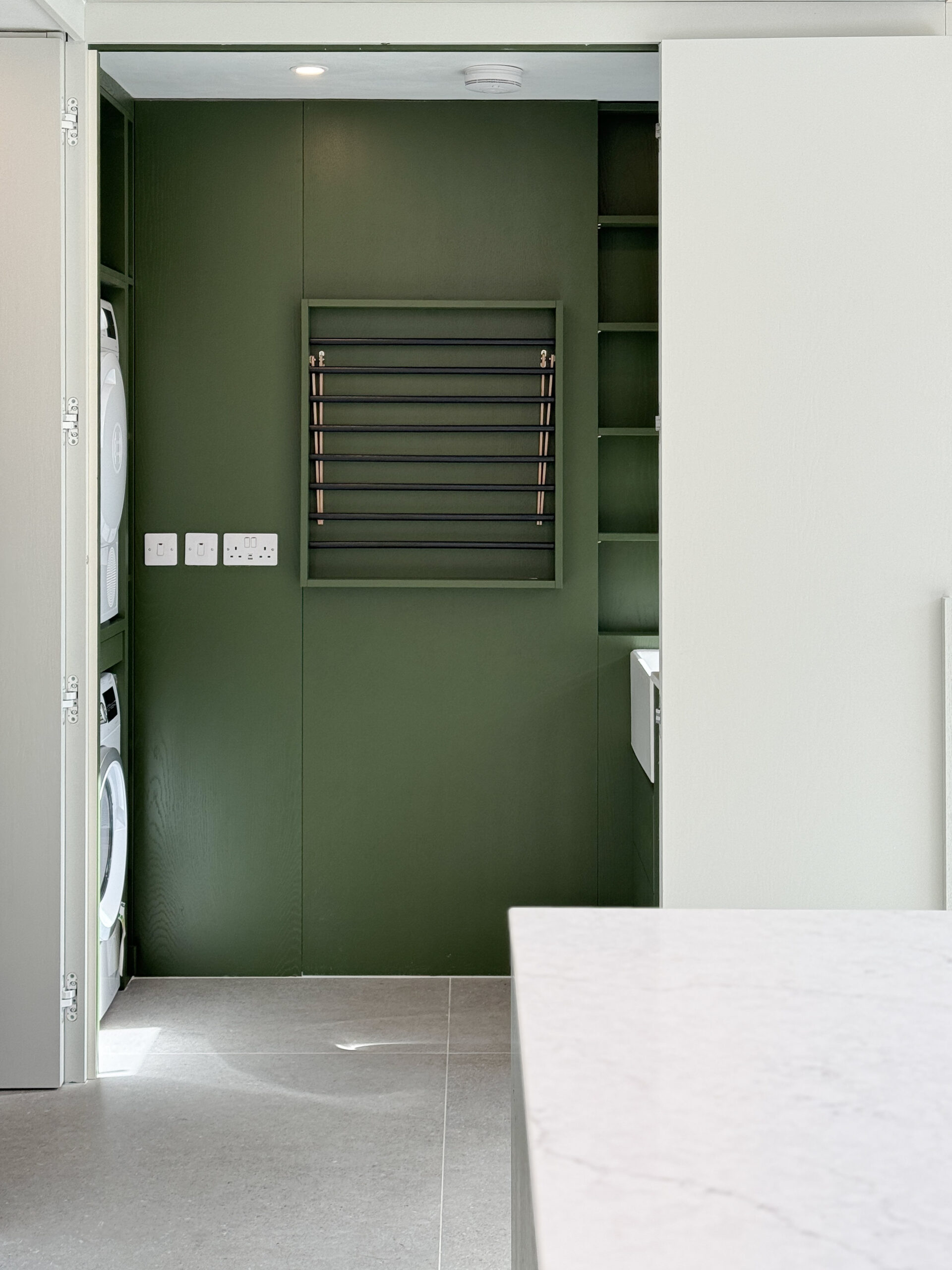 Custom made modern kitchen and utility space with large island, quartz worktop, hidden doors