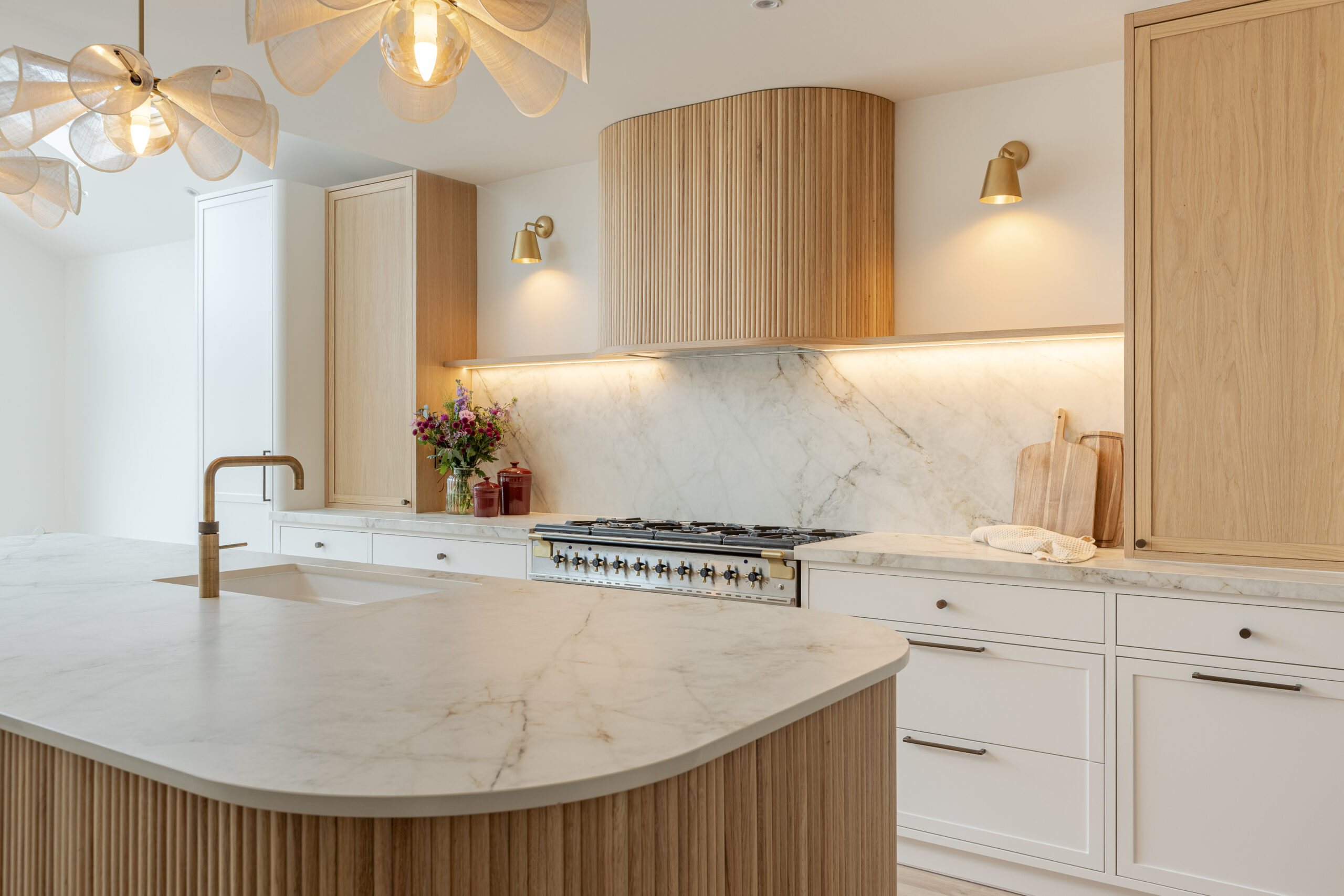 Custom made modern classical kitchen with large island, quartz worktop, and pendant lights and warm wood touch