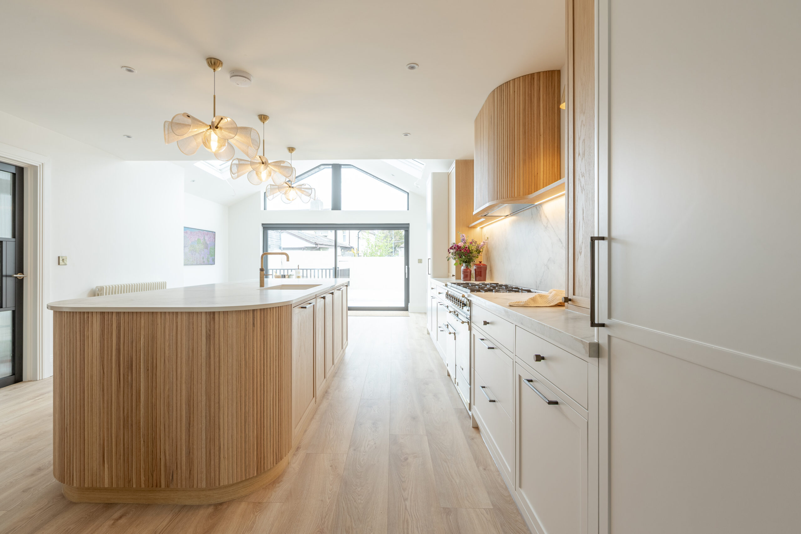 Custom made modern classical kitchen with large island, quartz worktop, and pendant lights and warm wood touch