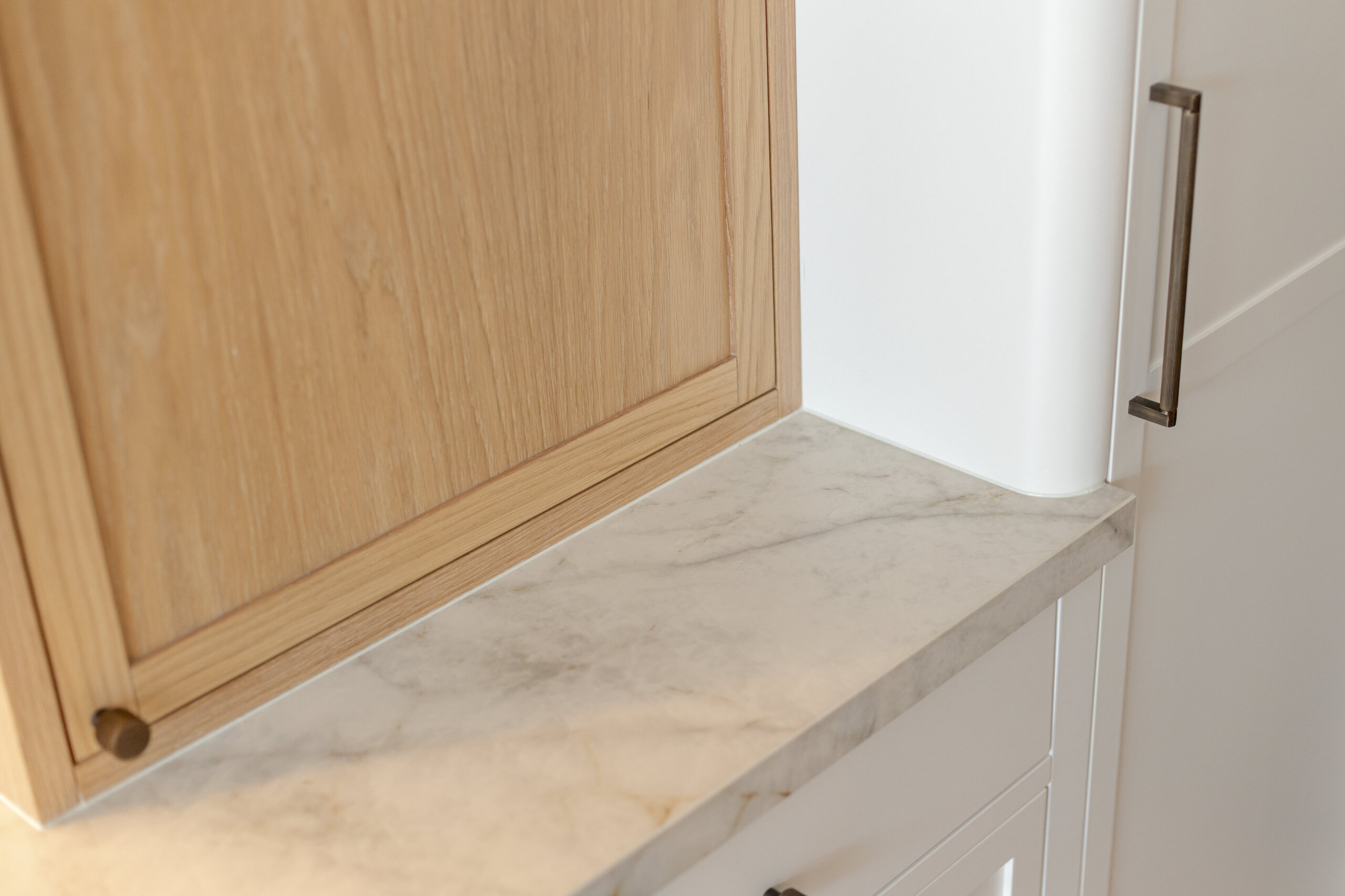 Custom made modern classical kitchen with large island, quartz worktop, and pendant lights and warm wood touch